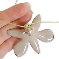 The cord is being tied to the back of a flower component.